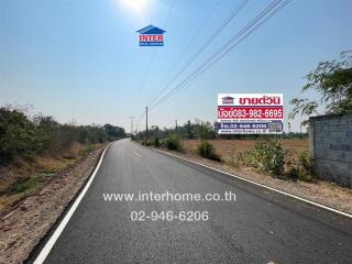 Wide road leading to a property location with contact information signs