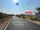 Wide road leading to a property location with contact information signs