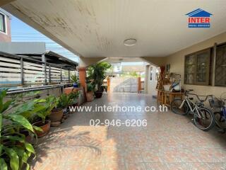 Spacious outdoor patio with shaded area, plants, and ample space for parking and bicycles