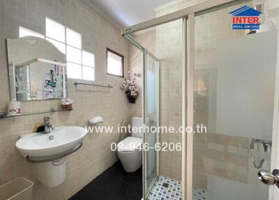 Spacious modern bathroom with glass shower stall and beige tiles