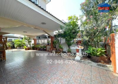 Spacious tiled patio with roof cover and decorative plants
