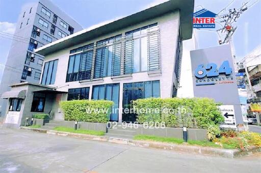 Modern commercial building exterior with large windows and prominent real estate signage