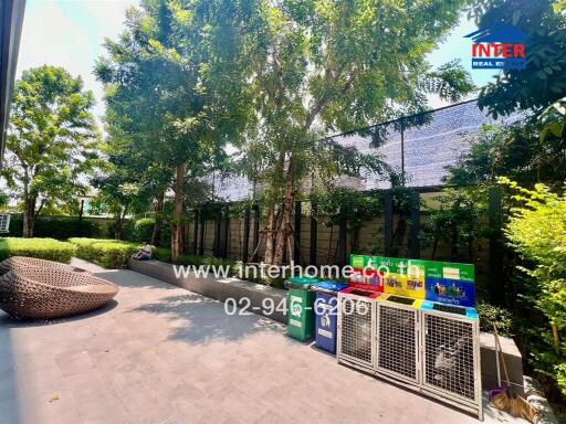 Leafy outdoor space with comfortable seating next to a building and greenery