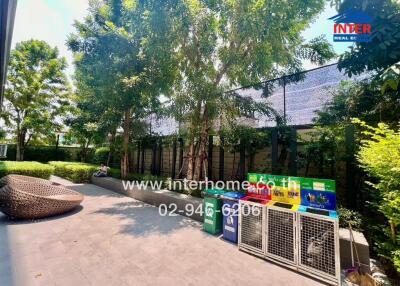 Leafy outdoor space with comfortable seating next to a building and greenery