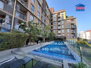 Luxurious outdoor pool area with modern seating and lush green plants in a residential apartment complex