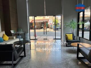Modern lobby area with large glass doors, comfortable seating, and indoor plants