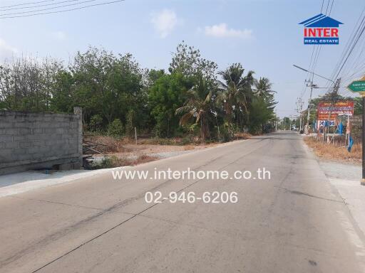 Paved road with trees and real estate signage