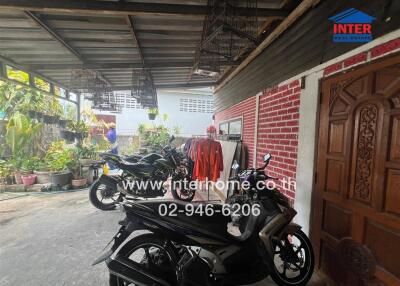 Outdoor covered parking space with motorcycles and potted plants