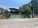 Traditional two-story house behind a decorative gate with a lush garden