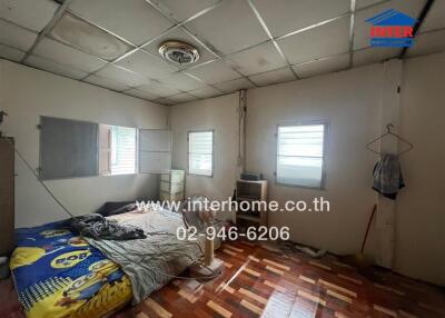 Unkempt bedroom with worn furnishings and exposed ceiling