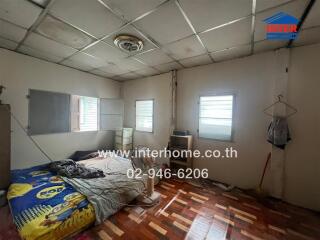 Unkempt bedroom with worn furnishings and exposed ceiling