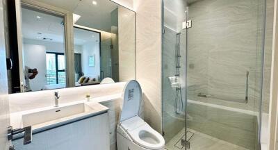 Modern bathroom interior with a glass shower, bath tub, and large mirror