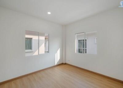 Bright and empty bedroom with wooden floors and multiple windows