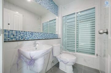 Modern bathroom with blue tile accents and shuttered windows