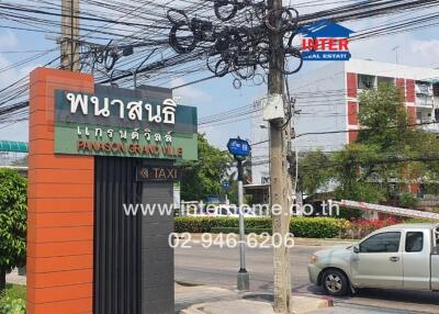 Street view of Panassa Grand Ville showing entrance sign and nearby apartment building