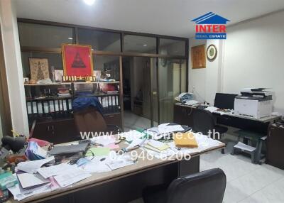 Cluttered office space with desk covered in papers and multiple electronic devices