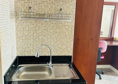 Compact kitchen area with wooden cabinets and stainless steel sink