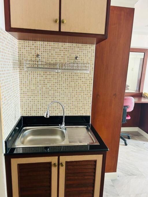 Compact kitchen area with wooden cabinets and stainless steel sink