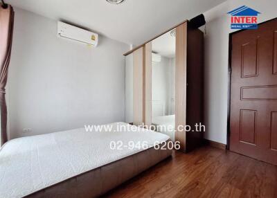 Modern bedroom with minimalistic design featuring a large bed, built-in wardrobe, and air conditioning