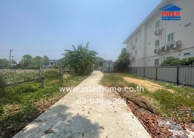 Pathway leading to modern apartment complex surrounded by foliage