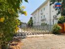 Exterior view of a gated residential building with surrounding greenery