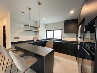 Modern spacious kitchen with black cabinetry and breakfast bar