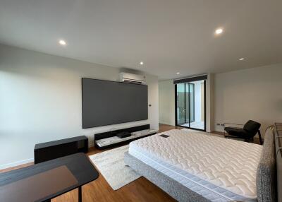 Spacious bedroom with large bed, flat-screen TV, and balcony access