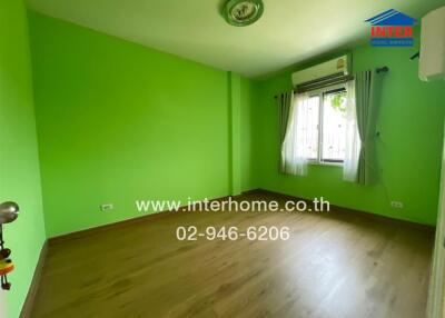 Spacious bedroom with bright green walls and wooden flooring