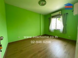 Spacious bedroom with bright green walls and wooden flooring