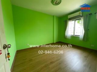 Bright bedroom with vibrant green walls and wooden flooring