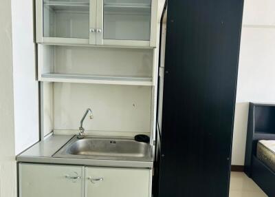 Compact kitchen with stainless steel sink, storage cabinets, and a refrigerator