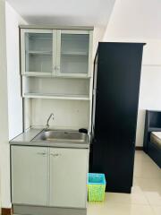 Compact kitchen with stainless steel sink, storage cabinets, and a refrigerator