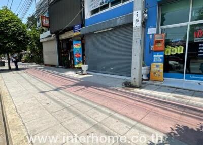 Street view of a commercial building with multiple shop fronts, including a closed shutter and visible business signs