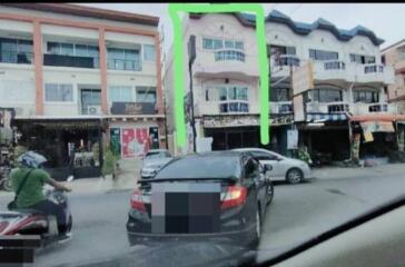 Street view of a multi-story residential building with commercial shops on the ground floor