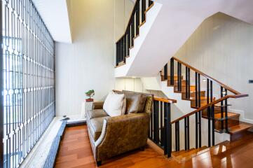 Elegant living room with leather sofa and wooden stairs