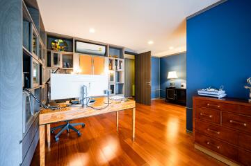Modern home office with bright workspace, blue walls, and hardwood floors