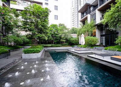 Luxurious outdoor communal swimming pool area with modern seating and lush greenery