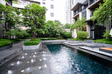 Luxurious outdoor communal swimming pool area with modern seating and lush greenery