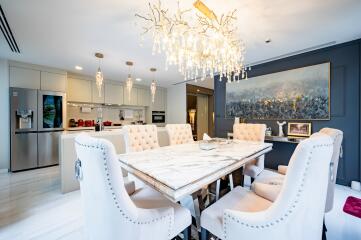 Elegant dining room with chandelier and modern kitchen in the background