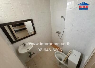 Compact modern bathroom with tiled walls featuring a shower, sink, and toilet