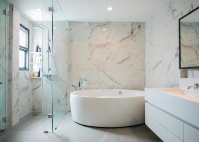 Luxurious modern bathroom with marble tiles, large bathtub, and glass shower