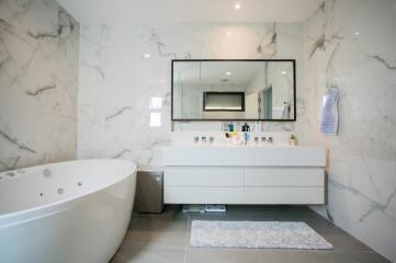 Spacious modern bathroom with large bathtub and marble walls