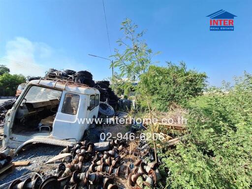 Cluttered outdoor area with damaged vehicle and scattered industrial materials