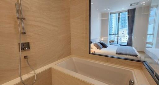 Modern bathroom with view into bedroom and urban skyline