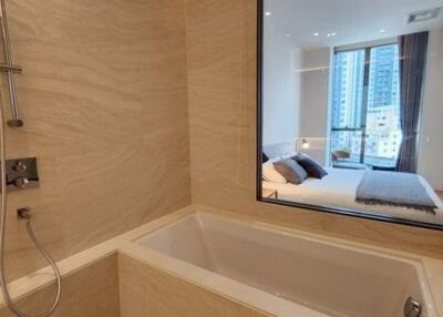 Modern bathroom with view into bedroom and urban skyline