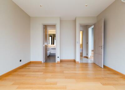 Spacious bedroom with wooden flooring and neutral walls