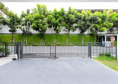 Spacious outdoor area with modern gray tiling and a lush green privacy hedge