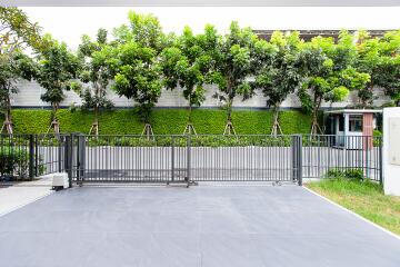 Spacious outdoor area with modern gray tiling and a lush green privacy hedge