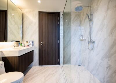 Modern bathroom with marble tiles, glass shower, and sleek fixtures