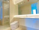 Modern bathroom with bright lighting, glass shower, and minimalist design